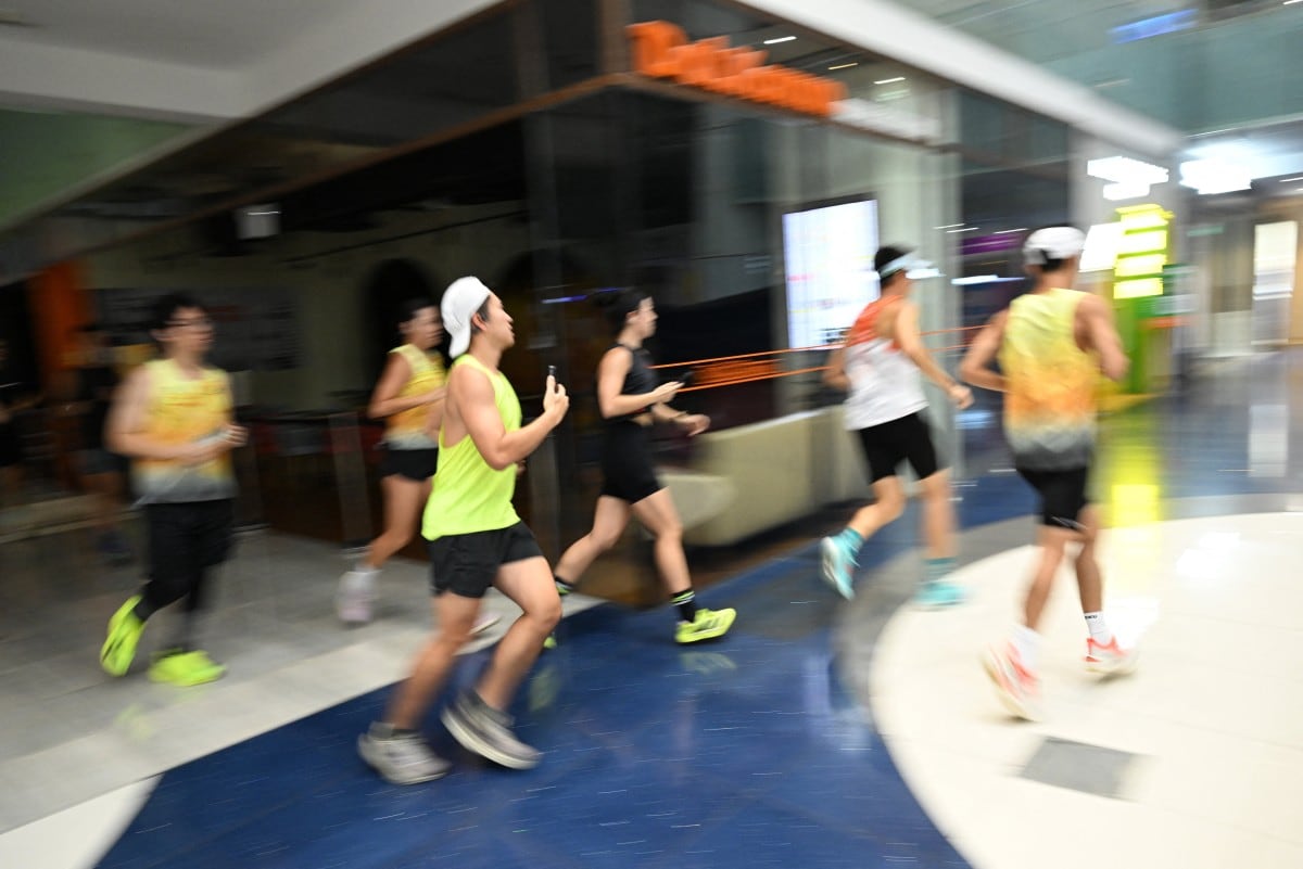 Aficionados al ejercicio físico corren dentro de un centro comercial debido a la bruma que afecta al exterior en Singapur, el 24 de octubre de 2026. (Foto de Roslan RAHMAN / AFP)