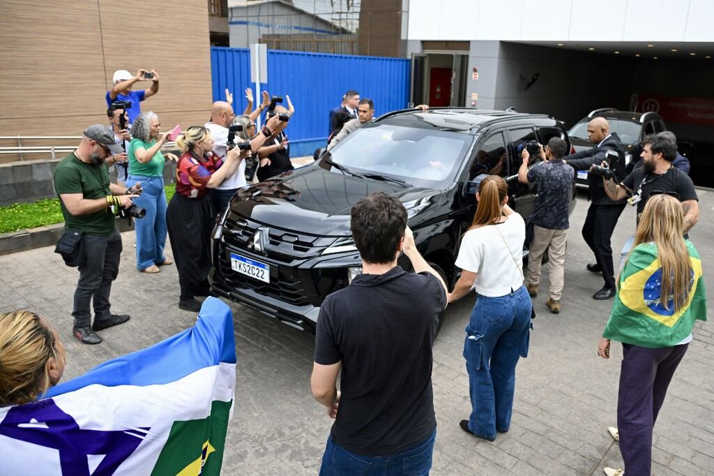 El vehículo que transportaba al expresidente brasileño Jair Bolsonaro fue rodeado por simpatizantes y periodistas al salir del Hospital DF Star en Brasilia el 17 de septiembre de 2025. (Foto de Evaristo Sa / AFP)