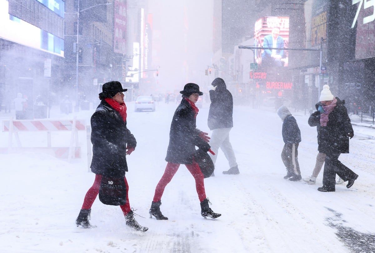 Personas cruzan la Sexta Avenida en Nueva York bajo la nieve el 25 de enero de 2026, mientras la tormenta invernal azota el noreste de EE.UU. | Crédito: CHARLY TRIBALLEAU / AFP