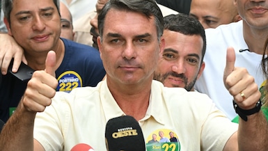 El senador de derecha y candidato presidencial del Partido Liberal (PL), Flavio Bolsonaro, levanta el pulgar al salir de un centro de votación tras emitir su voto. (Foto de MAURO PIMENTEL / AFP).