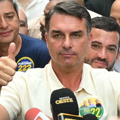 El senador de derecha y candidato presidencial del Partido Liberal (PL), Flavio Bolsonaro, levanta el pulgar al salir de un centro de votación tras emitir su voto. (Foto de MAURO PIMENTEL / AFP).