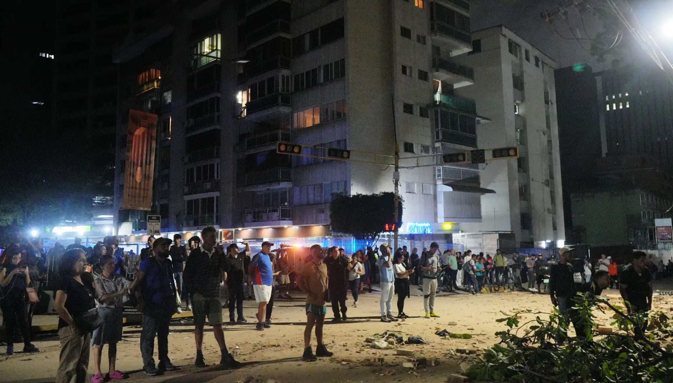Varias personas permanecen de pie frente a edificios dañados tras el terremoto en Caracas, Venezuela, el miércoles 24 de junio de 2026. (Foto AP/Adrian Naranjo)