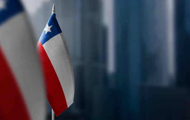 Small flags of Chile on a blurry background of the city.