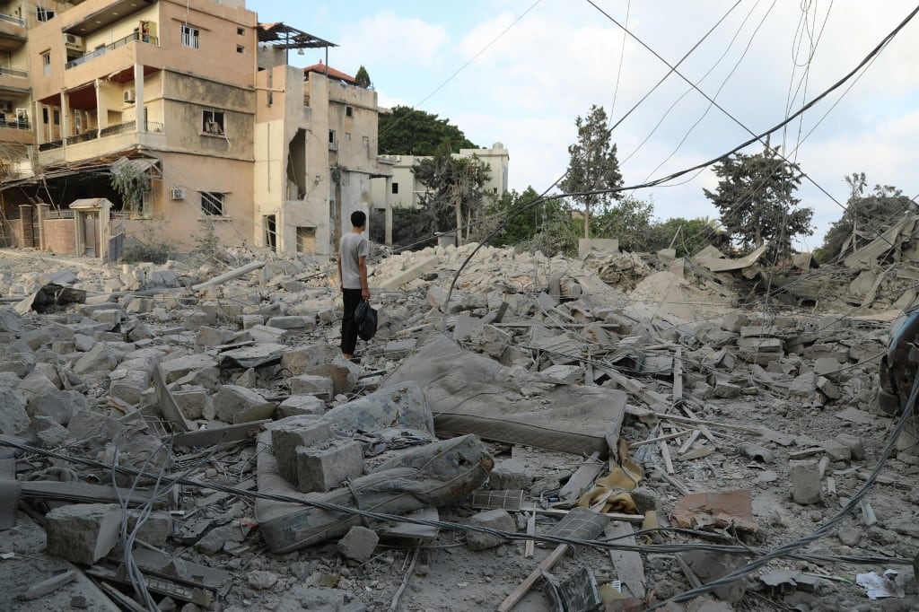 A man stands amid debris following Israeli airstrikes that hit the previous day, near the archaeological site of the Roman baths in the southern Lebanese city of Tyre on June 8, 2026. On June 7, the Israeli military issued an evacuation warning for most of Tyre and its surroundings. The coastal city shelters thousands of displaced people and has been heavily bombed since the fighting began. (Photo by KAWNAT HAJU / AFP) /