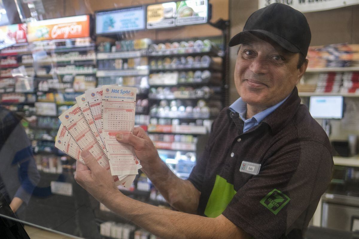 Un cajero muestra boletos de lotería Mega Millions en una tienda de conveniencia 7-Eleven en Chino Hills, California, el 28 de julio de 2022 (Foto: AFP)