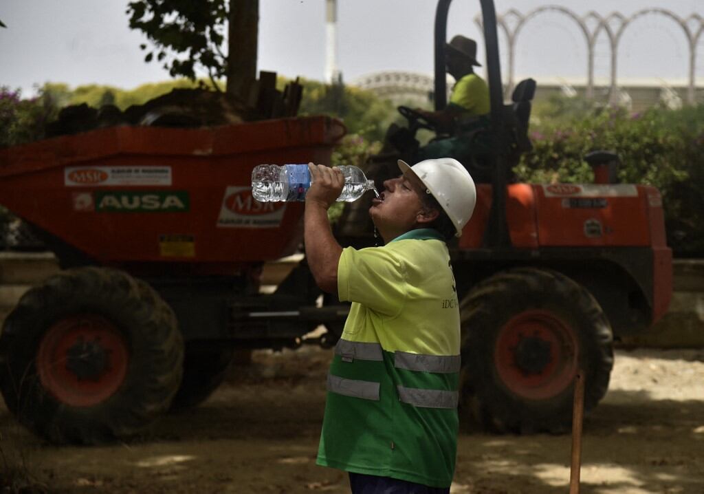 Un trabajador de construcción bebe agua para combatir el calor abrasador durante una ola de calor en Sevilla el 13 de junio de 2022. (Foto de CRISTINA QUICLER / AFP)