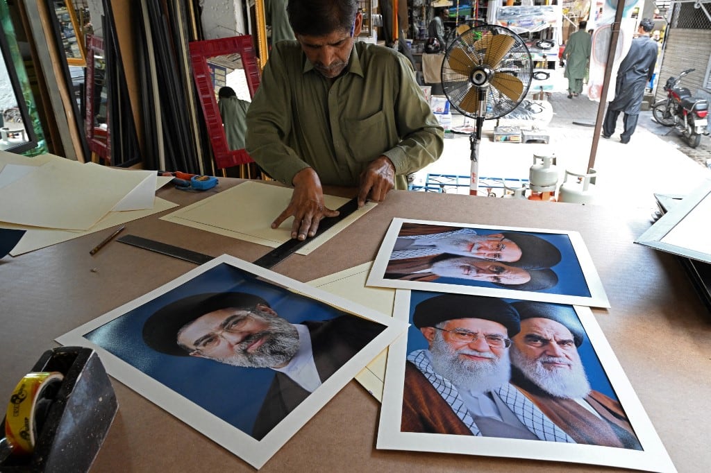 Un artesano prepara retratos del recién elegido líder supremo de Irán, Mojtaba Khamenei (izquierda), junto a los líderes asesinados, el ayatolá Ruhollah Khomeini (derecha) y el ayatolá Ali Khamenei (centro), en un mercado de Islamabad el 29 de abril de 2026. (Foto de Aamir QURESHI / AFP)