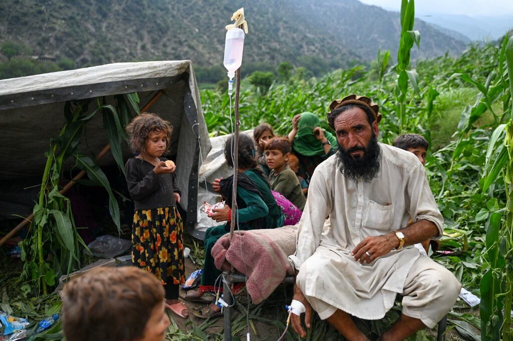 Un hombre afgano herido recibe suero intravenoso en un campo de maíz, tras los terremotos en la aldea de Mazar Dara, en el distrito de Nurgal, provincia de Kunar, en el este de Afganistán, el 1 de septiembre de 2025. (Foto de Wakil Kohsar / AFP)