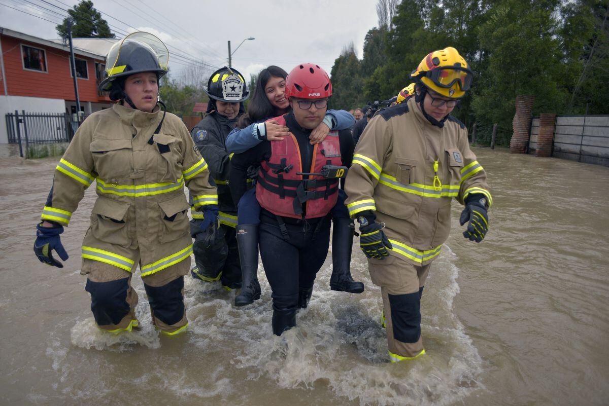 Los bomberos evacuan a los residentes atrapados en la ciudad inundada de Cabrero, en la región central del Bío Bío de Chile, el 21 de agosto de 2023, después de que las fuertes lluvias provocaran el desbordamiento del río Laja (Foto: Guillermo Salgado / AFP)