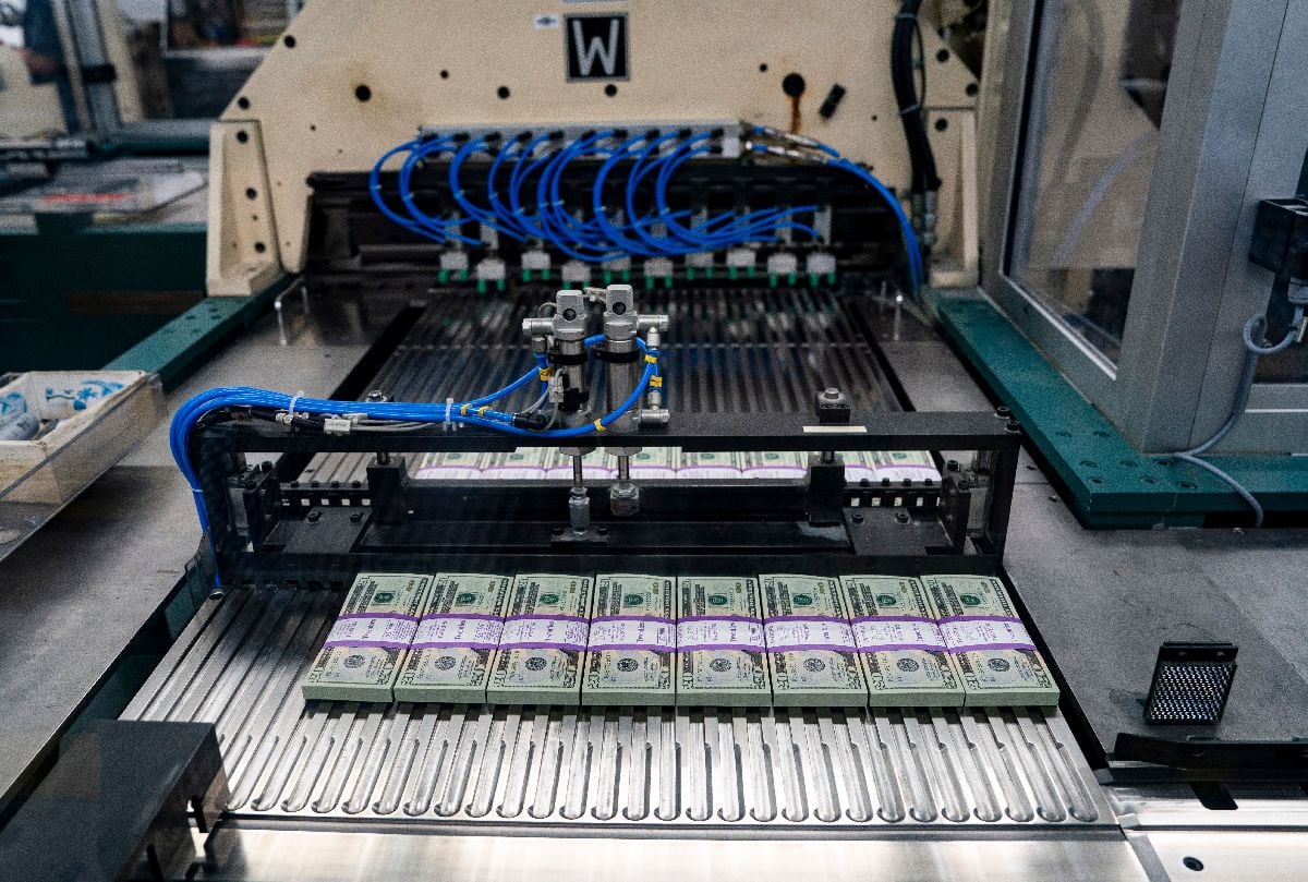 Billetes de veinte dólares pasan por una gran máquina de inspección y empaquetado tras ser agrupados con bandas en la Oficina de Grabado e Impresión de EE.UU., en Washington D. C., el martes 21 de mayo de 2024.