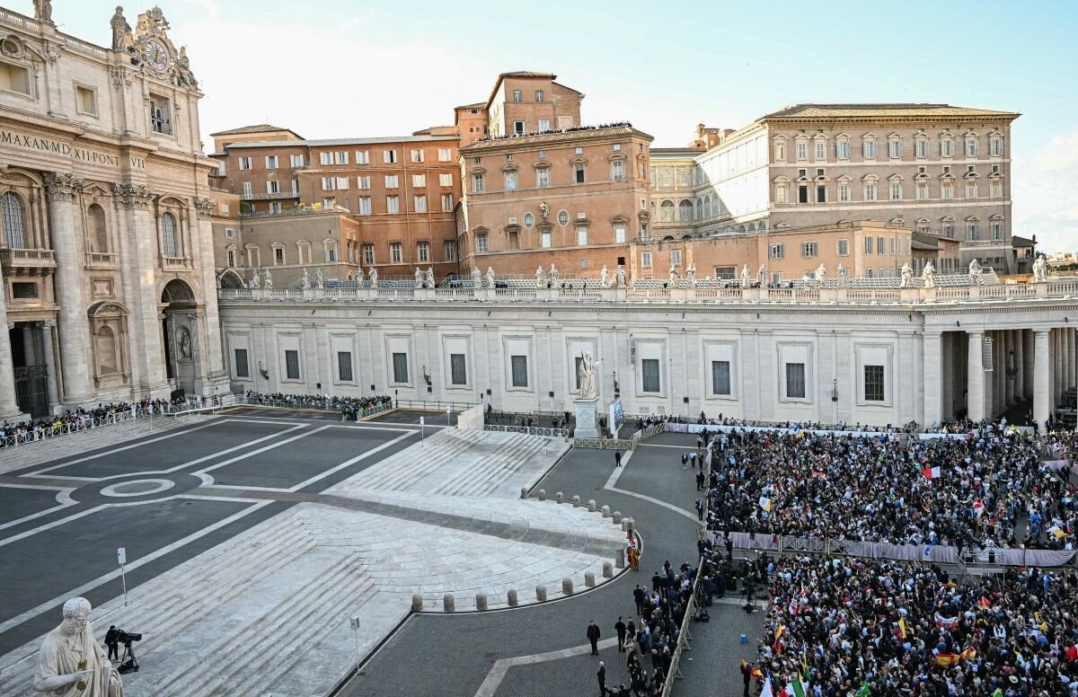 La gente reacciona en la Plaza de San Pedro, junto a la Basílica de San Pedro (izq.), mientras los cardenales anunciaban la elección de un nuevo papa durante su cónclave secreto en el Vaticano, el 8 de mayo de 2025. El jueves, una columna de humo blanco salía de la chimenea de la Capilla Sixtina, lo que indicaba que los 133 cardenales presentes habían elegido un nuevo papa. (Foto de Gabriel BOUYS / AFP)