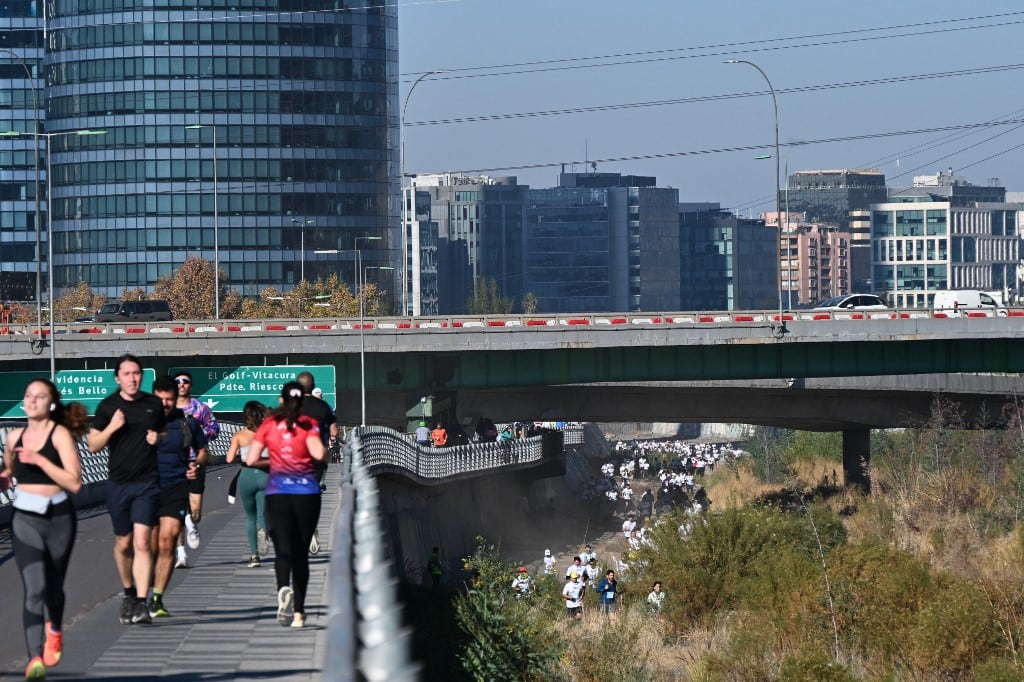 Corredores participan en una carrera a lo largo de las orillas del río Mapocho (derecha) en Santiago, el 17 de mayo de 2026. Las aguas contaminadas del río Mapocho, que atraviesa la capital chilena, alguna vez avergonzaron a los residentes, quienes ahora lo disfrutan tras su limpieza. (Foto de RODRIGO ARANGUA / AFP)