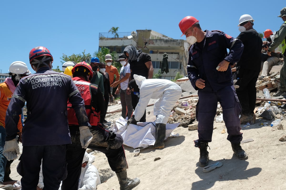 Bomberos y voluntarios rescatan un cuerpo sin vida durante los trabajos de remoción de escombros en La Guaira, Venezuela, el 7 de julio de 2026. (Xaume Olleros / EFE)