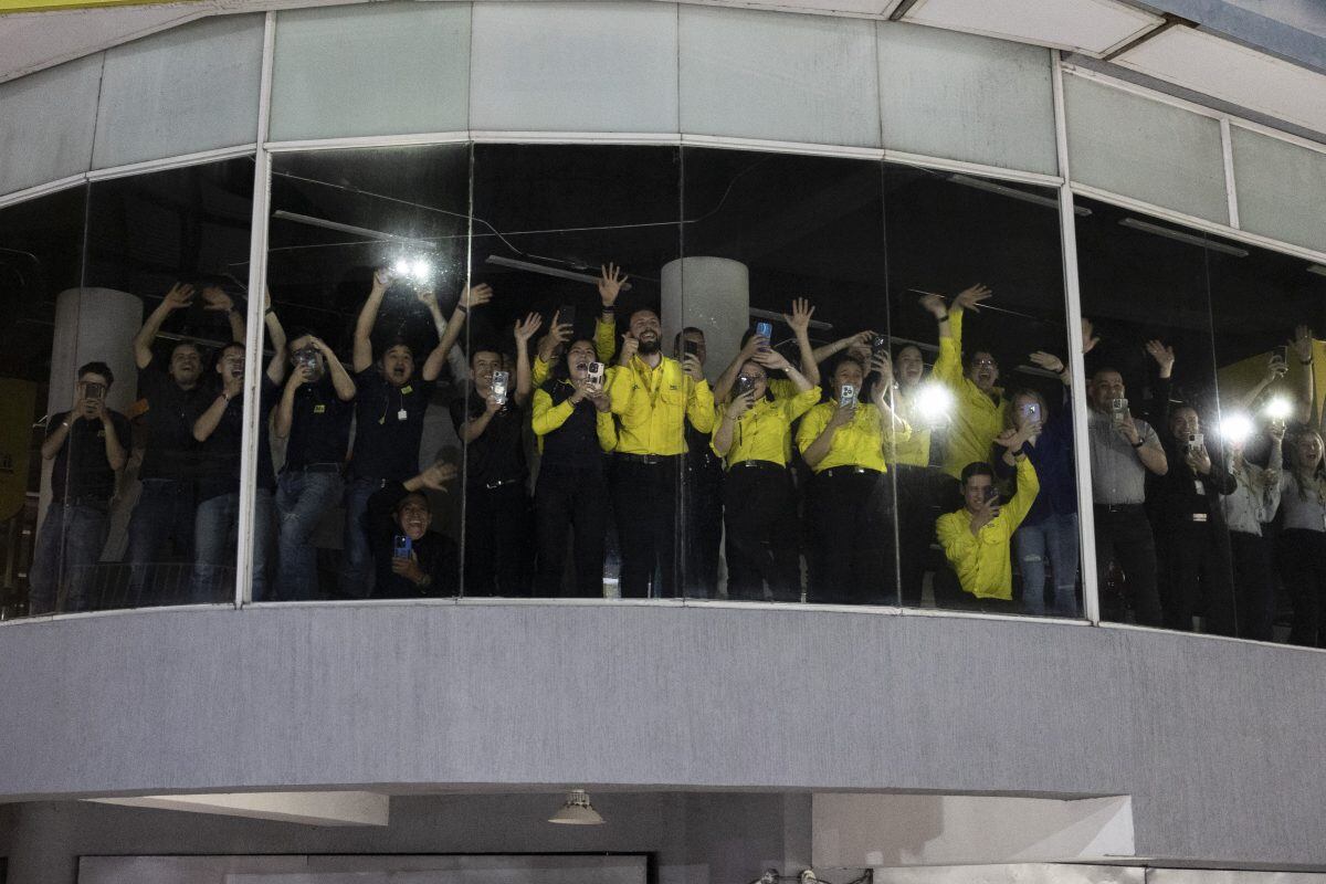 Empleados se agolpan contra los escaparates de las tiendas para tener la oportunidad de ver pasar la caravana.