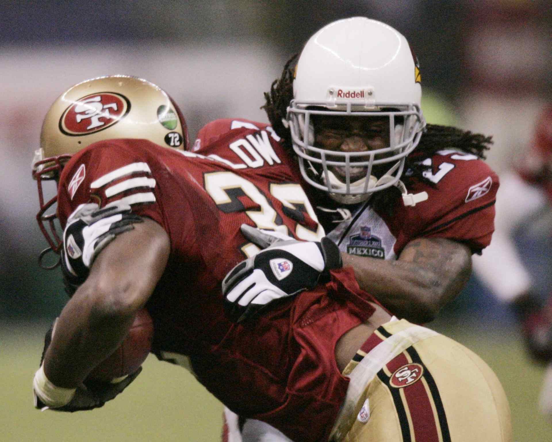 Kevan Barlow #32 de los San Francisco 49ers es derribado por Chike Okeafor #56 de los Arizona Cardinals el 2 de octubre de 2005 en el Estadio Azteca de la Ciudad de México durante el primer partido de la temporada regular de la NFL. AFP PHOTO/Alfredo ESTRELLA (Foto por ALFREDO ESTRELLA / AFP)