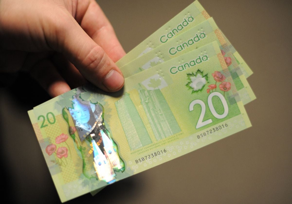 Un hombre exhibe billetes de 20 dólares canadienses (Foto: Nicholas Kamm / AFP)