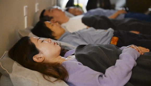 Esta foto tomada el 8 de diciembre de 2023 muestra a personas durmiendo durante una sesión de sanación con sonido en el estudio en Pekín | Foto: AFP