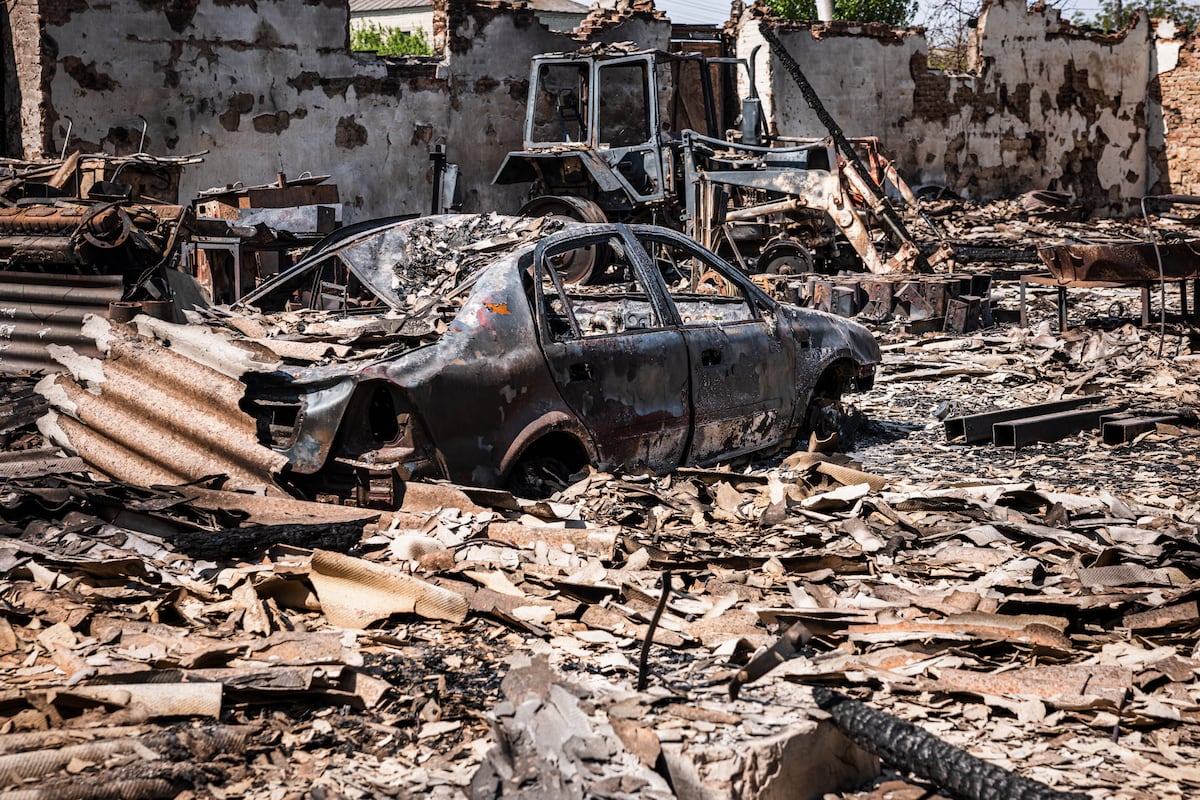 Esta fotografía tomada el 11 de mayo de 2022 muestra un automóvil y un tractor quemados después del bombardeo de las fuerzas rusas en la ciudad de Orikhiv, cerca de Zaporizhzhia, en el este de Ucrania. (Dimitar DILKOFF / AFP)