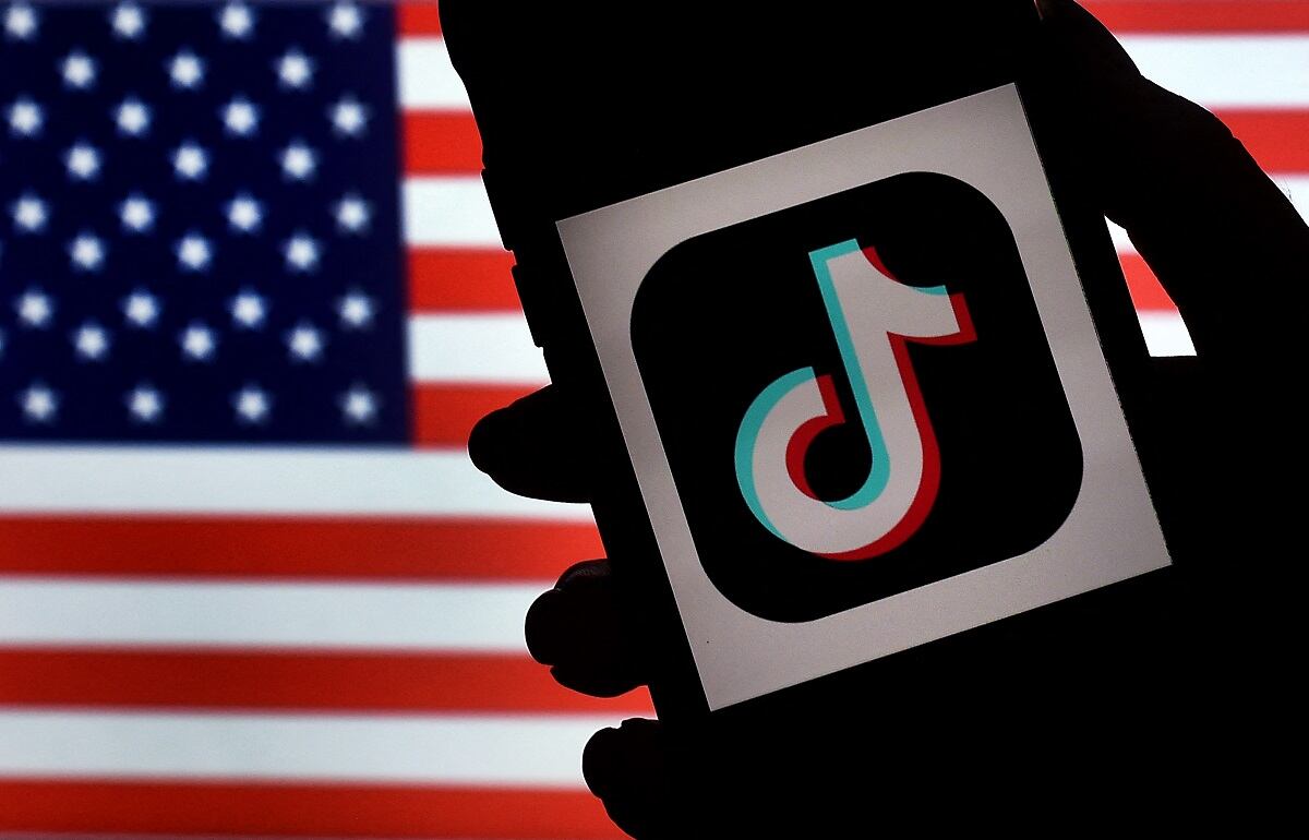 El logotipo de la aplicación de redes sociales, TikTok, se muestra en la pantalla de un iPhone sobre un fondo de bandera de EE. UU. en Arlington, Virginia. (Foto de Olivier DOULIERY / AFP)