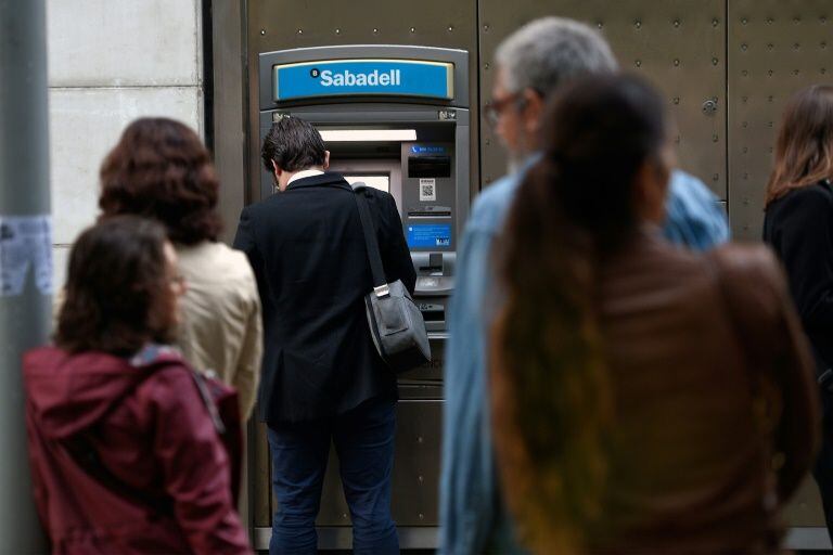 Un cliente saca dinero de un cajero automático del Banco Sabadell en Barcelona. (Foto: AFP)