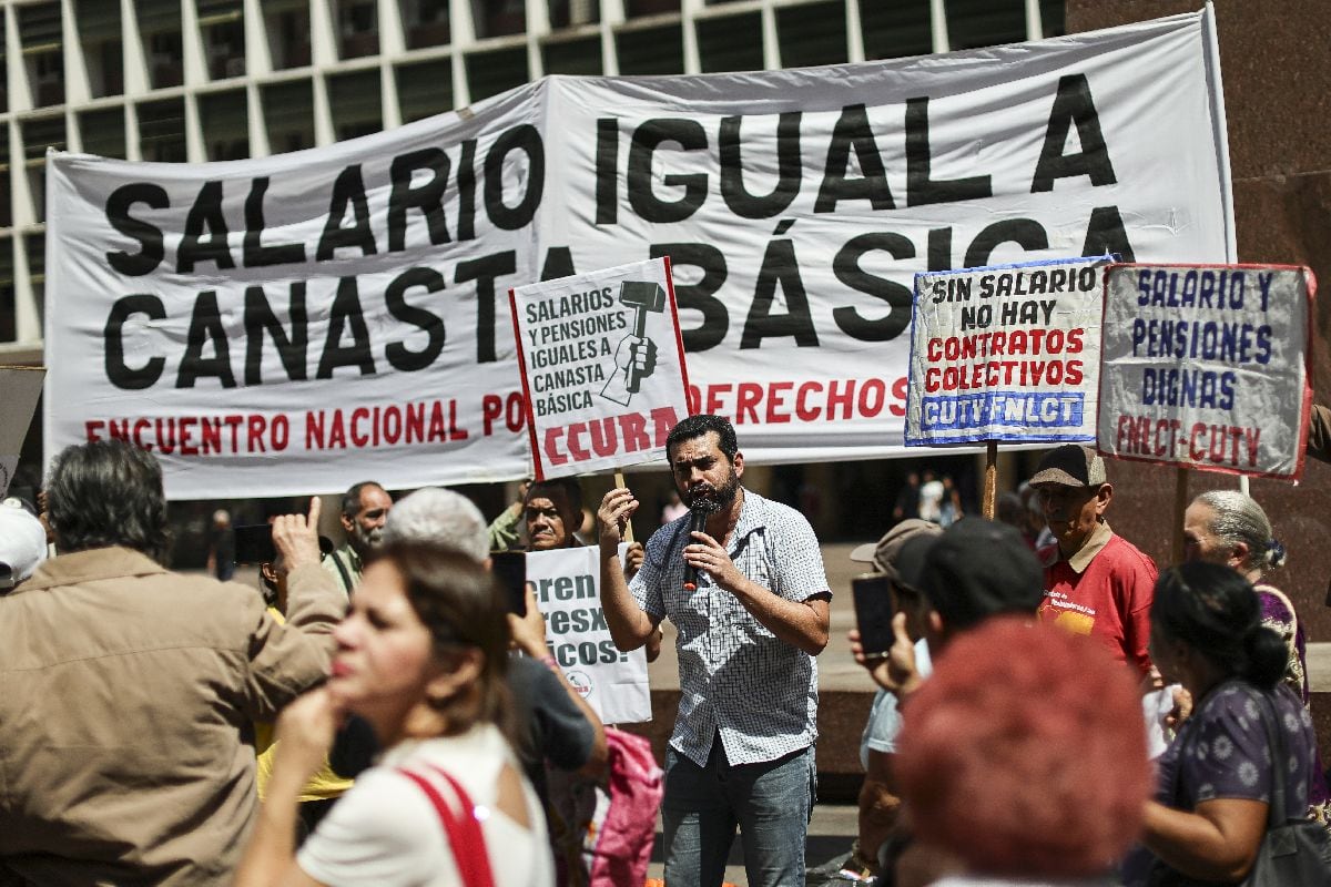 Trabajadores y jubilados participan con pancartas y consignas en una manifestación en favor de un aumento salarial frente al Ministerio de Trabajo en Caracas, el 26 de febrero.