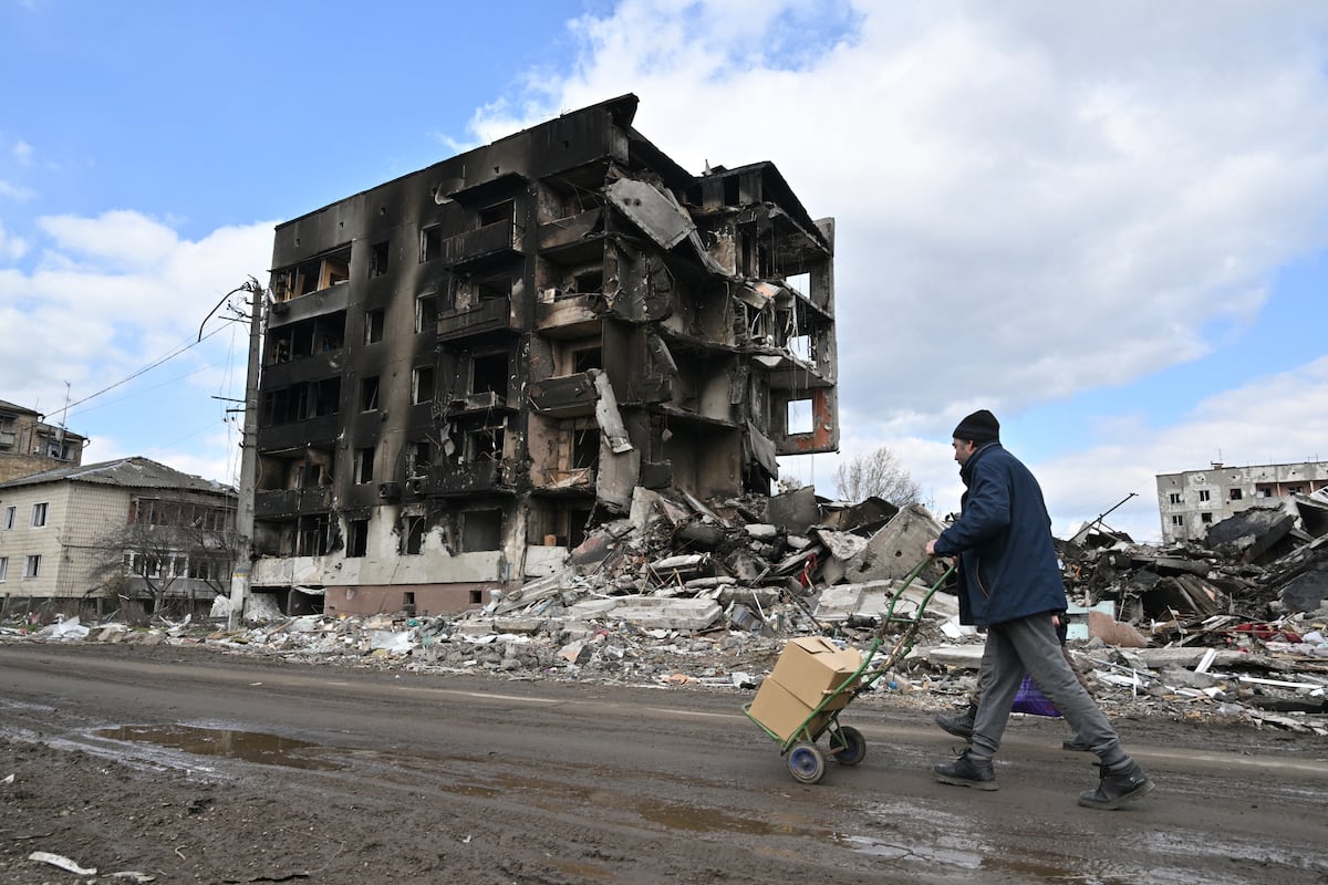 (ARCHIVOS) En esta foto de archivo tomada el 4 de abril de 2022, un hombre empuja un carro frente a edificios destruidos en la ciudad de Borodianka, al noroeste de Kyiv, en medio de la invasión rusa de Ucrania. - AFP presenta un paquete de 60 fotografías de archivo que muestran la vida cotidiana de los ucranianos durante los seis meses de la invasión rusa. (Foto de Sergei SUPINSKY / AFP)