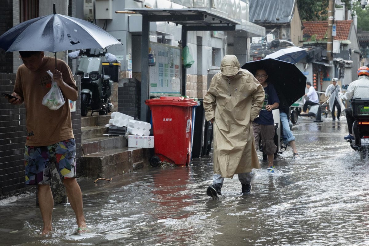 Personas caminan tras las fuertes lluvias en la zona de Hutong de Pekín, China, el 7 de julio de 2026. Foto: EFE/EPA/JESSICA LEE