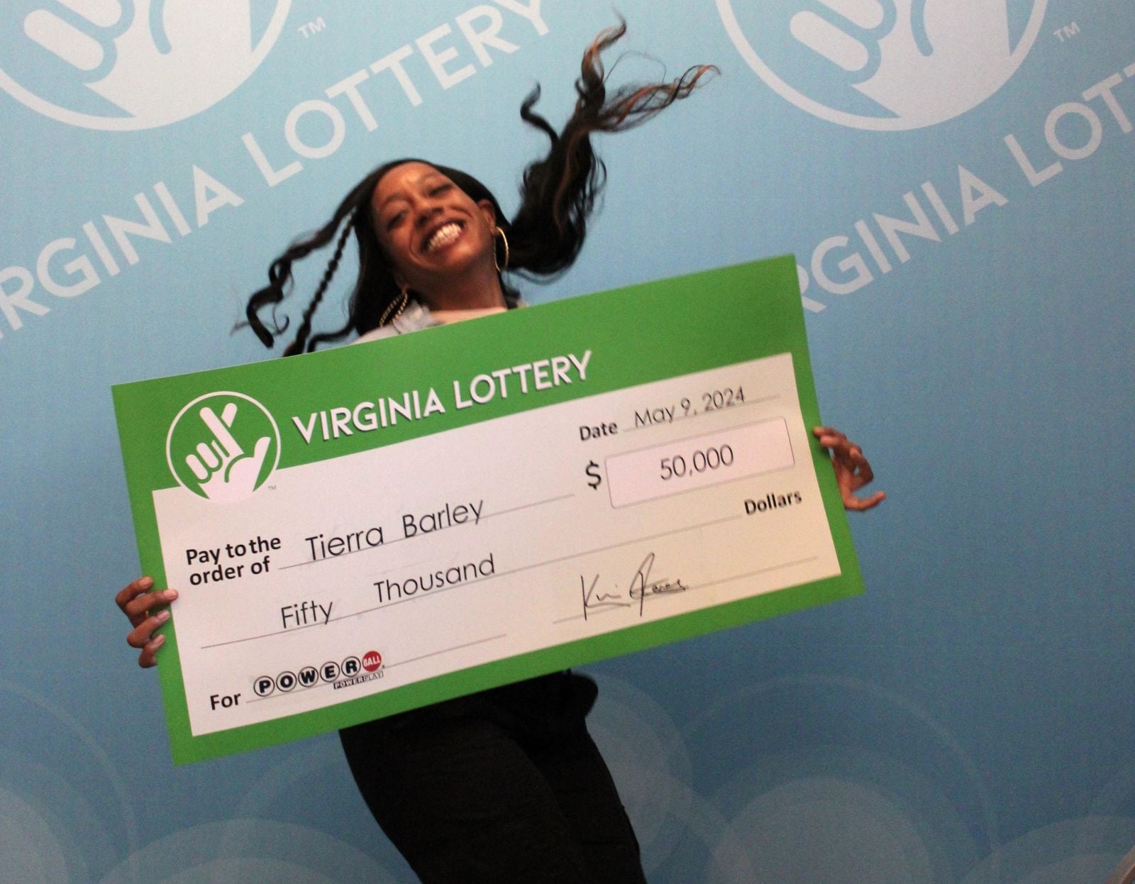 Tierra Barley posa feliz con el cheque que la muestra como ganadora de 50 mil dólares de Powerball (Foto: Lotería de Virginia)