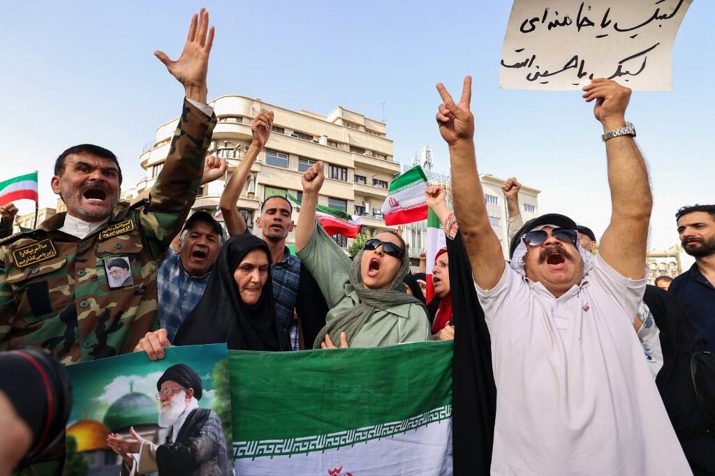 Iranians lift flags and placards during a rally protesting the US attack on Iran in Enghelab Square in Tehran on June 22, 2025. Iran's President Masoud Pezeshkian condemned US strikes on nuclear sites on June 22, saying in his first response that the attack revealed Washington was "behind" Israel's military campaign in the Islamic republic. (Photo by ATTA KENARE / AFP)