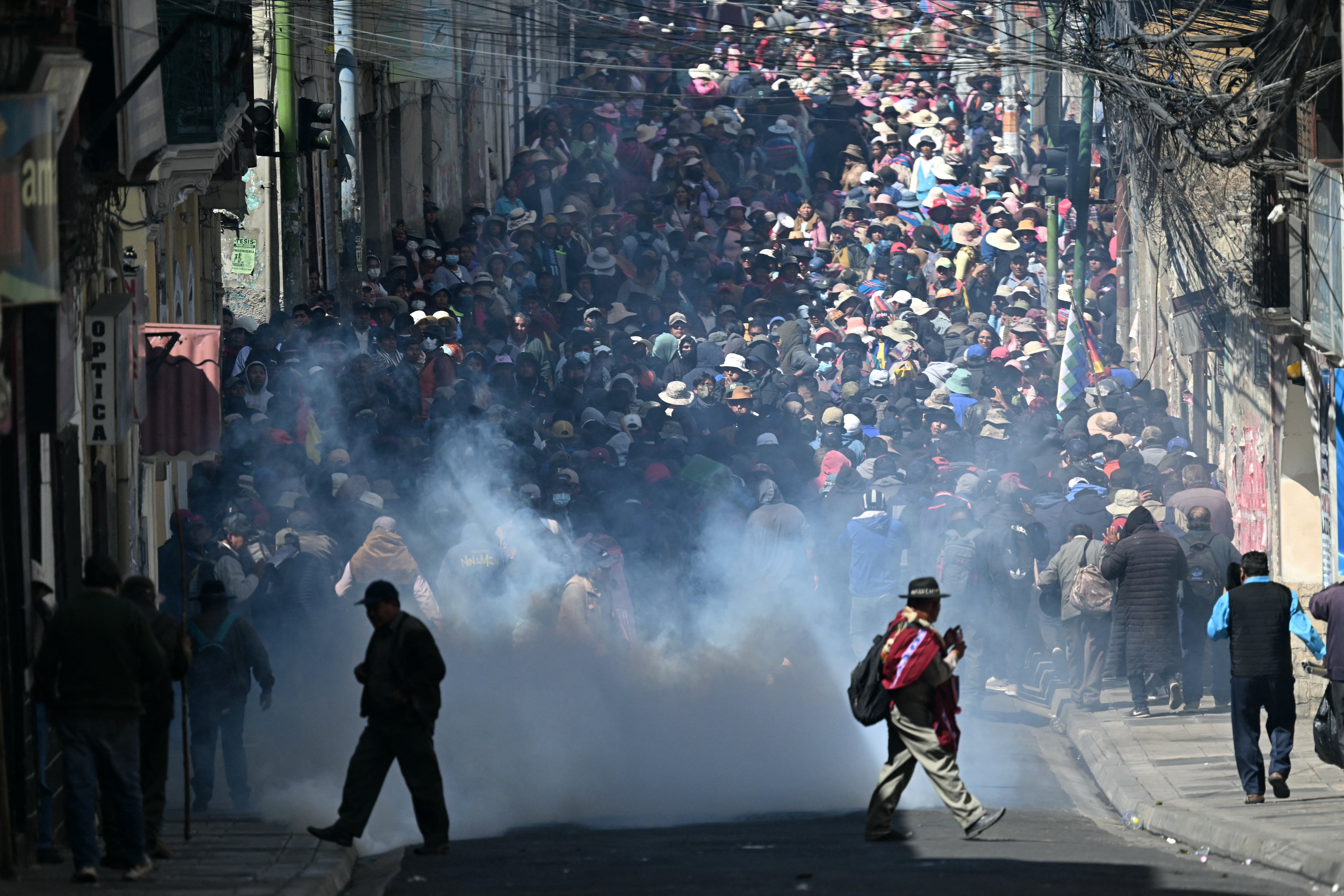 Manifestantes huyen de los gases lacrimógenos durante enfrentamientos con la policía antidisturbios en una protesta que exige la renuncia del presidente boliviano Rodrigo Paz. (Foto de AIZAR RALDES / AFP).