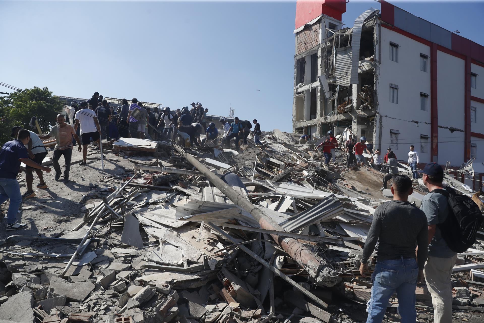 Personas caminan sobre los escombros de un edificio colapsado en Cali tras el terremoto que sacudió Colombia. (EFE/ Ernesto Guzmán).