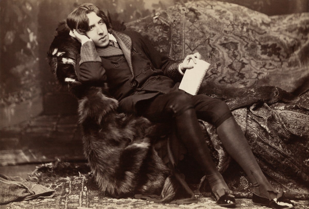 Oscar Wilde reclinado con su libro "Poemas" en Nueva York (1882). | Crédito: Napoleon Sarony