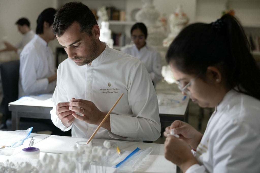 El pastelero francés Bastien Blanc-Tailleur prepara la decoración para un pastel de bodas en su estudio de Saint-Remy-les-Chevreuse, al suroeste de París, el 10 de abril de 2026. (Foto de Thomas SAMSON / AFP)