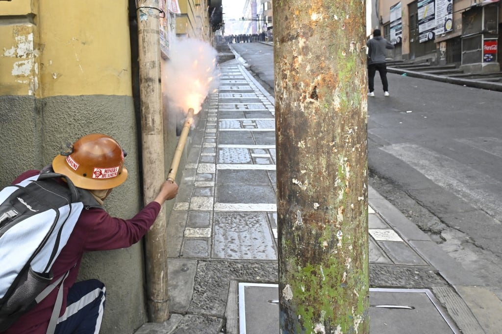 Un minero lanza una bengala durante enfrentamientos con la policía antidisturbios en una protesta que exige la renuncia del presidente boliviano Rodrigo Paz en La Paz, el 18 de mayo de 2026. Los bolivianos han salido a las calles durante las últimas dos semanas, bloqueando las carreteras de acceso a La Paz e interrumpiendo la entrega de alimentos, medicinas y otros bienes a la capital, mientras exigen mejores salarios, ayuda económica y la renuncia del presidente de centroderecha Rodrigo Paz en medio de una grave crisis económica. (Foto de AIZAR RALDES / AFP)
