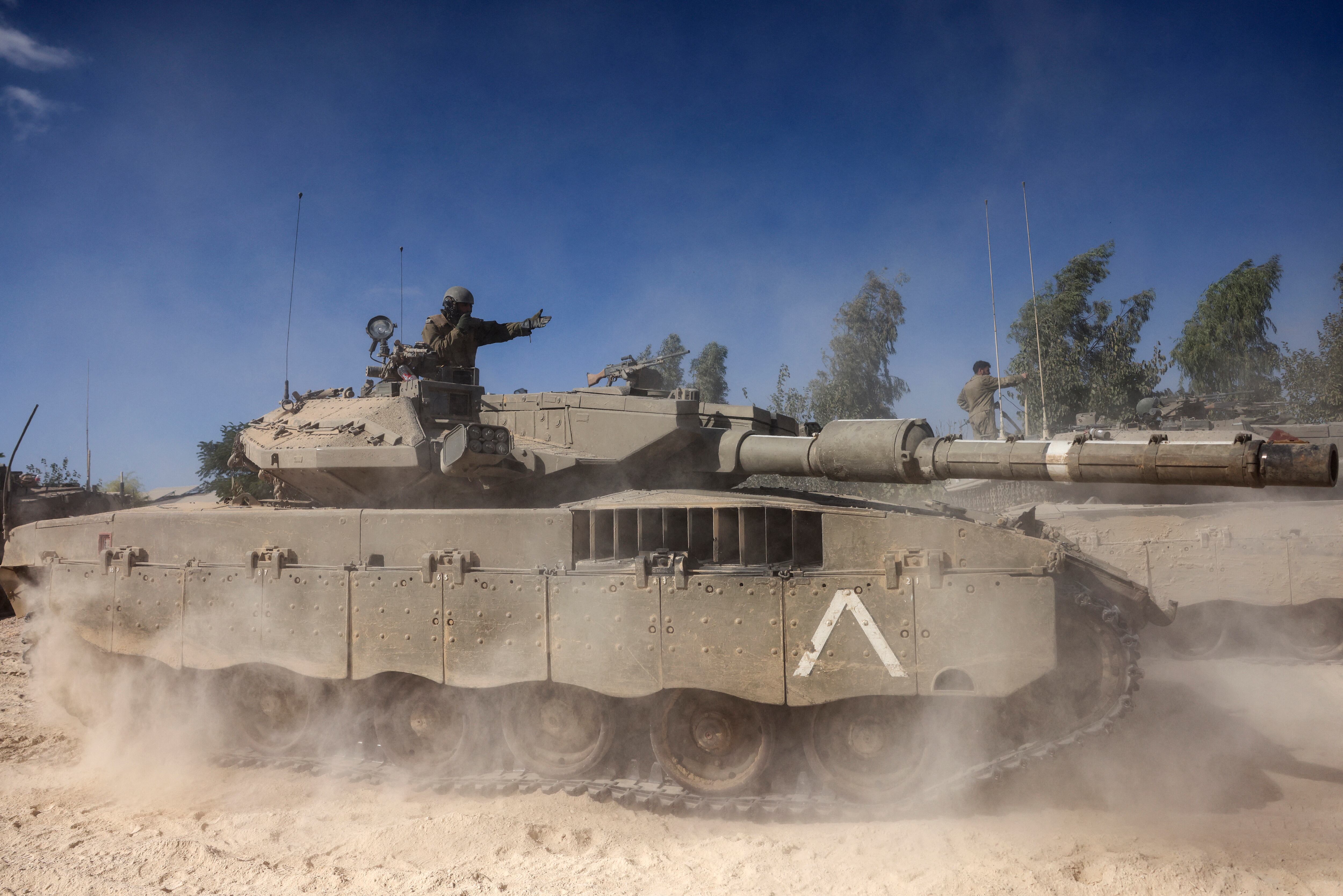 Un soldado israelí grita instrucciones desde lo alto de un tanque Merkava estacionado en las afueras del Kibbutz Beeri, cerca de la frontera con la Franja de Gaza, el 20 de octubre de 2023, en medio de las batallas en curso entre Israel y el grupo palestino Hamás. (Foto de RONALDO SCHEMIDT/AFP)