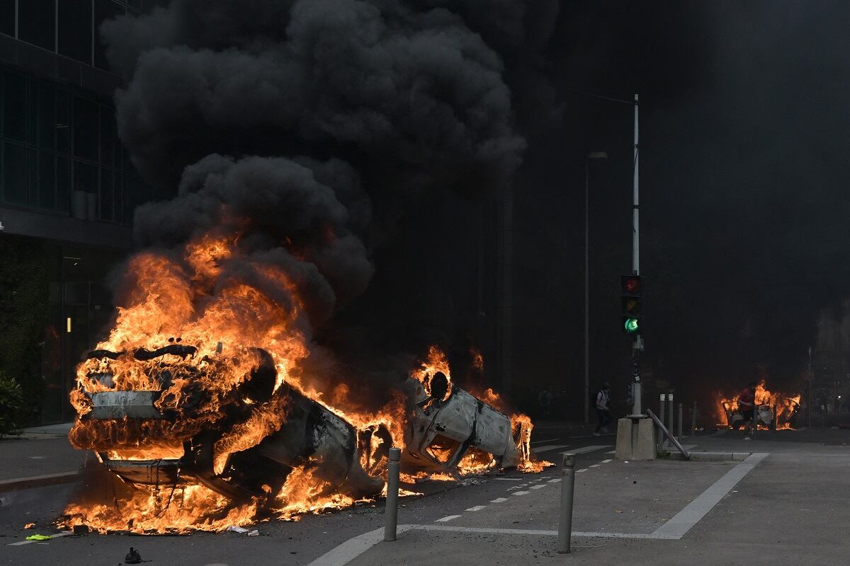 Una fotografía muestra autos ardiendo en la calle al final de una marcha de conmemoración de un conductor adolescente asesinado a tiros por un policía, en el suburbio parisino de Nanterre, el 29 de junio de 2023. (Foto de Alain JOCARD / AFP)