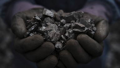 A worker's hands handling coal coke at a facility in Norte de Santander, Colombia, Saturday, March 4, 2023.