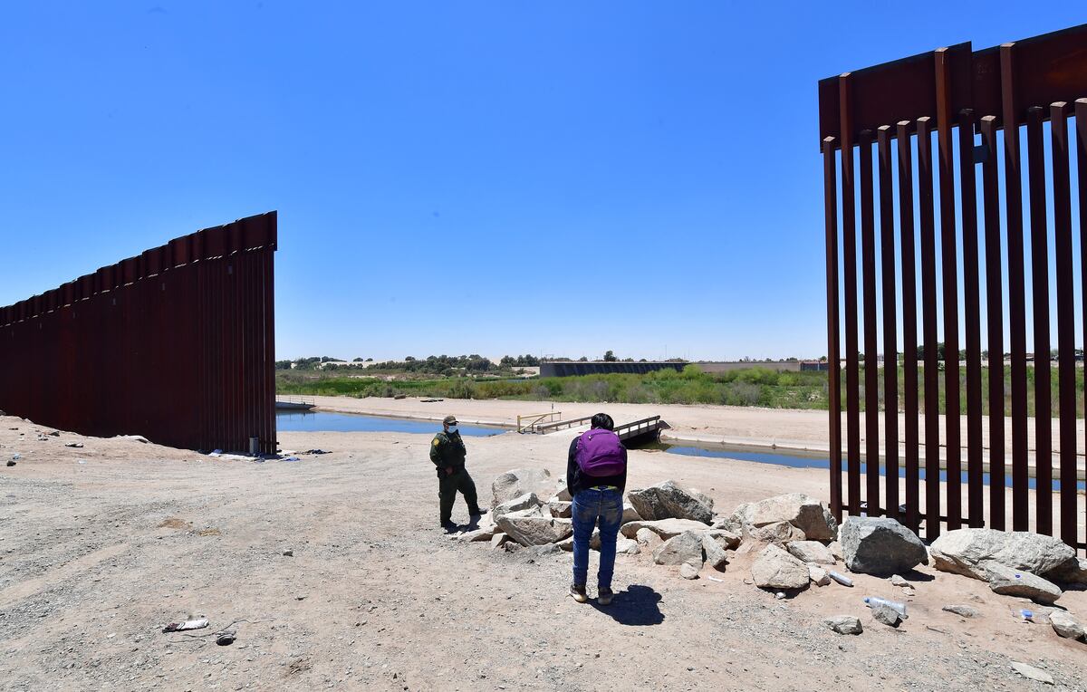 A US Border Patrol officer speaks with a migrant after he crossed into the US from Mexico through a gap in the border wall separating Algodones, Mexico, from Yuma, Arizona, on May 16, 2022. - A US Federal judge is expected to make a ruling on health policy Title 42 which has been used at the border to expel illegal immigrants due to the Covid-19 pandemic. (Photo by Frederic J. BROWN / AFP)