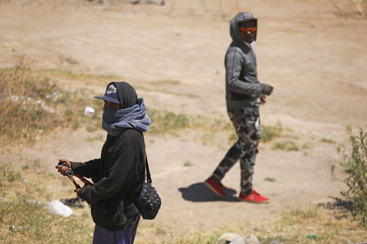 Migrantes que buscan ingresar a Estados Unidos intentan cortar una cerca de alambre de púas instalada por la Guardia Nacional de Texas en la frontera con Ciudad Juárez, estado de Chihuahua, México, el 13 de mayo de 2024 (Foto: Herika Martinez / AFP)