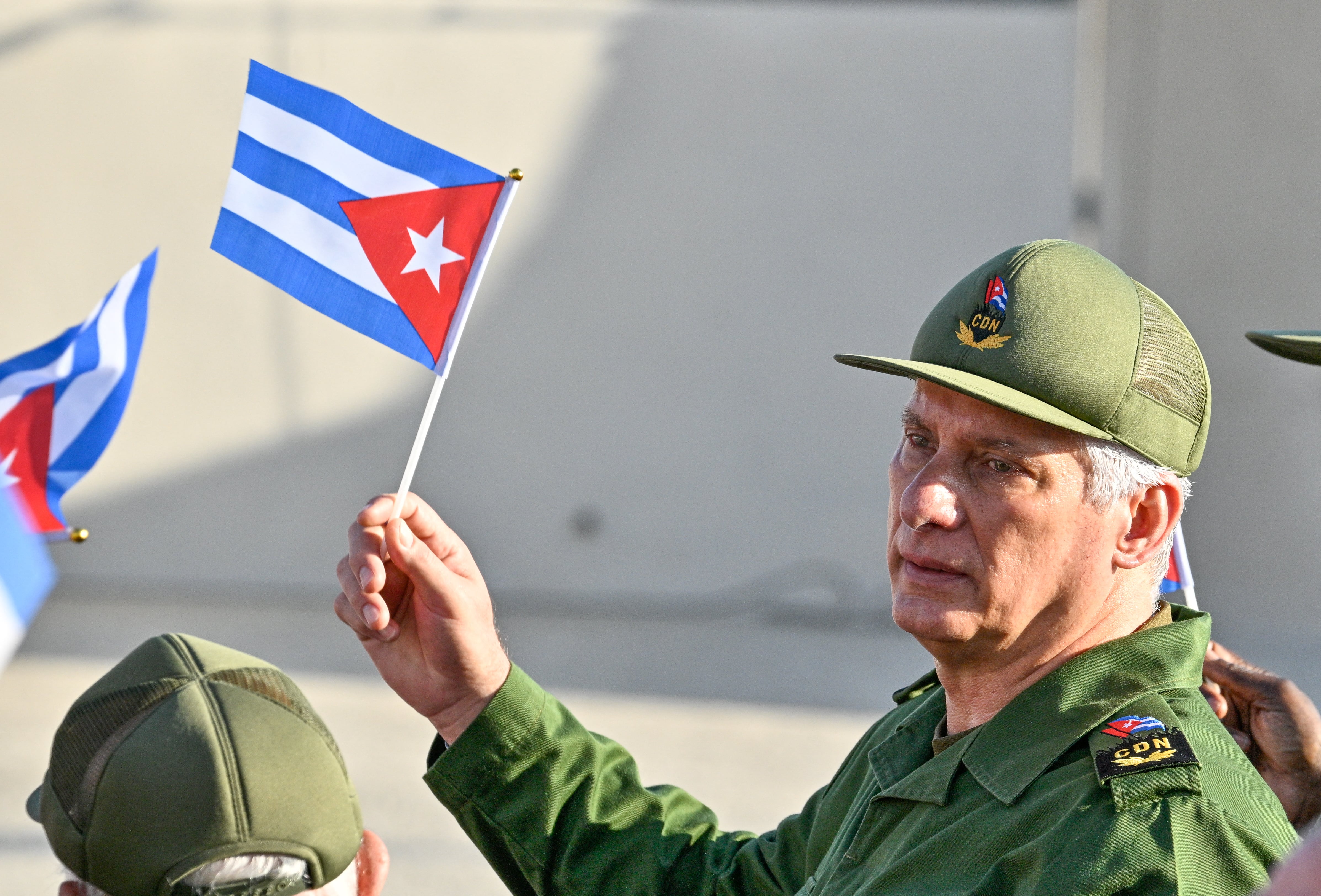 El presidente de Cuba, Miguel Díaz-Canel, sostiene una bandera cubana durante una manifestación en apoyo del expresidente cubano Raúl Castro, de 94 años. (Foto de ADALBERTO ROQUE / AFP).