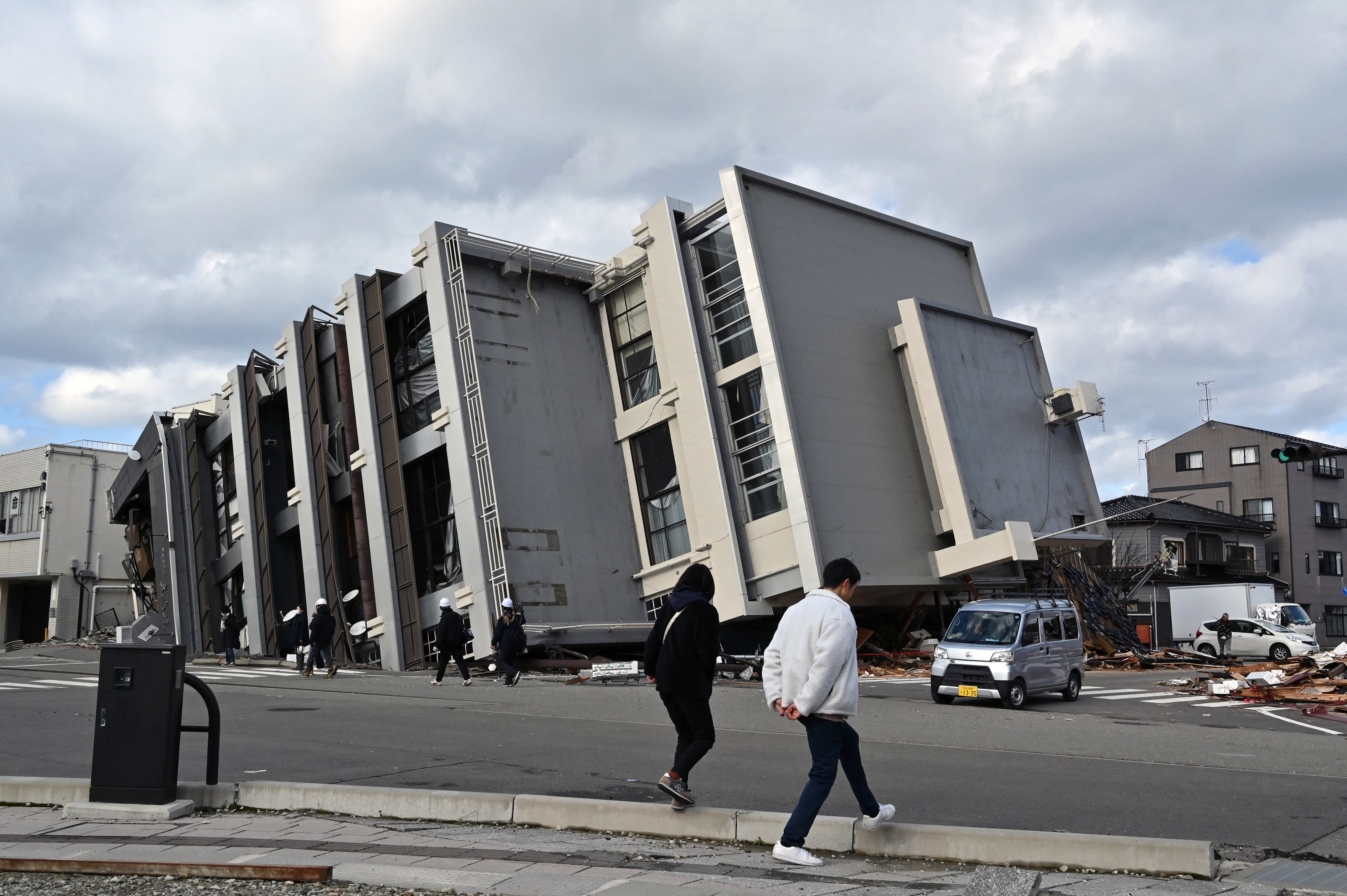 La gente camina frente a un edificio derrumbado en la ciudad de Wajima, prefectura de Ishikawa, el 4 de enero de 2024, después de que un gran terremoto de magnitud 7,6 sacudiera Japón. (Foto de Kazuhiro NOGI / AFP).