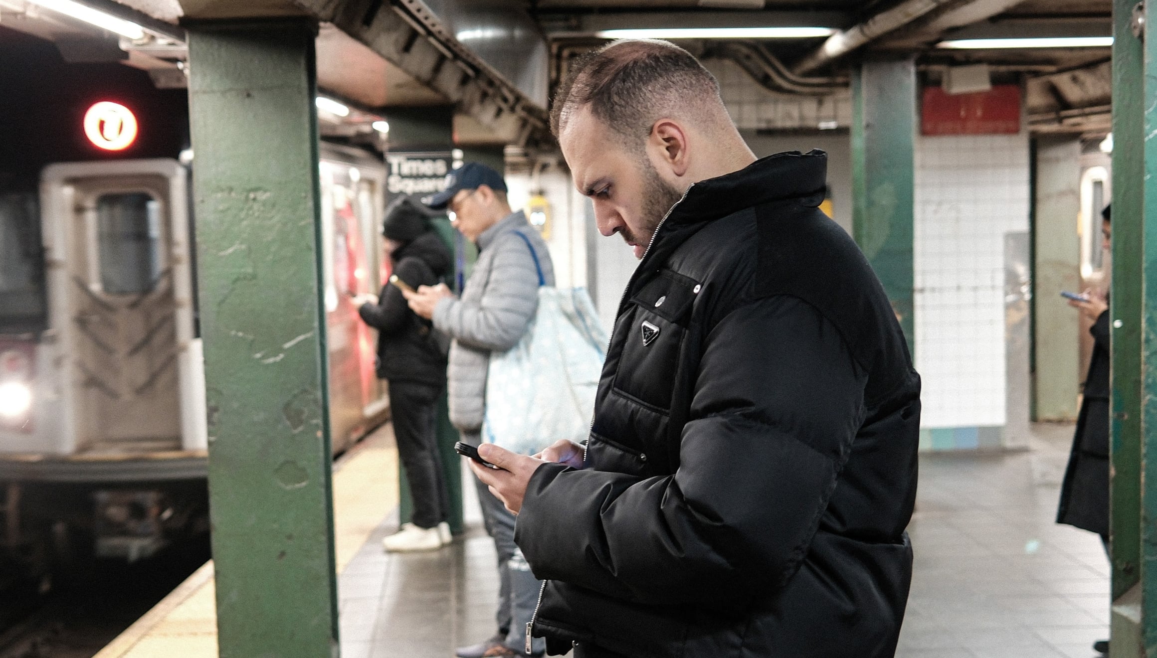 Ciudadano de Nueva York revisando su teléfono celular mientras espera el metro (Foto: AFP)
