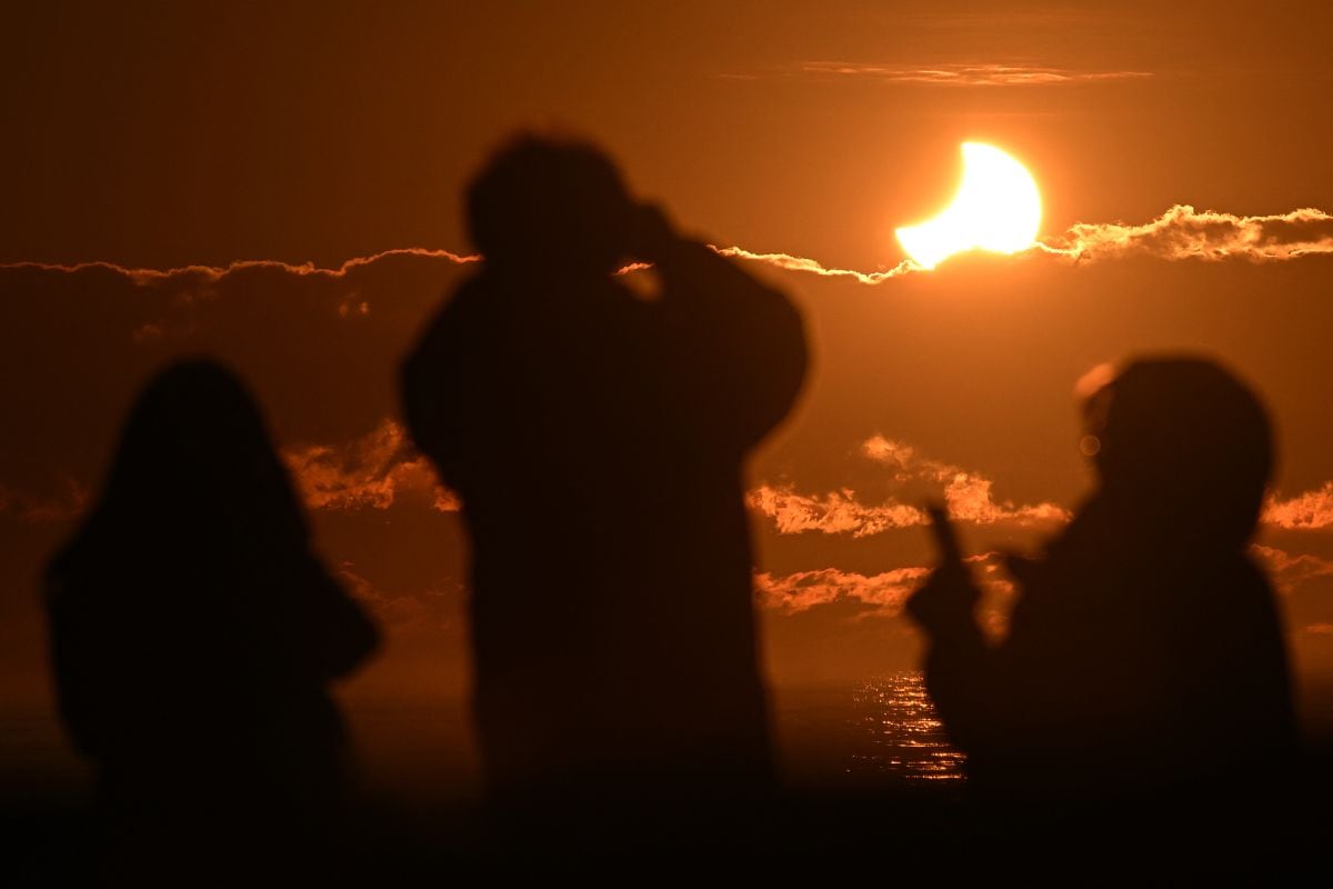 La gente observa un eclipse solar parcial en New Brighton, un suburbio costero de Christchurch, el 22 de septiembre de 2025. (Foto de Sanka Vidanagama / AFP)