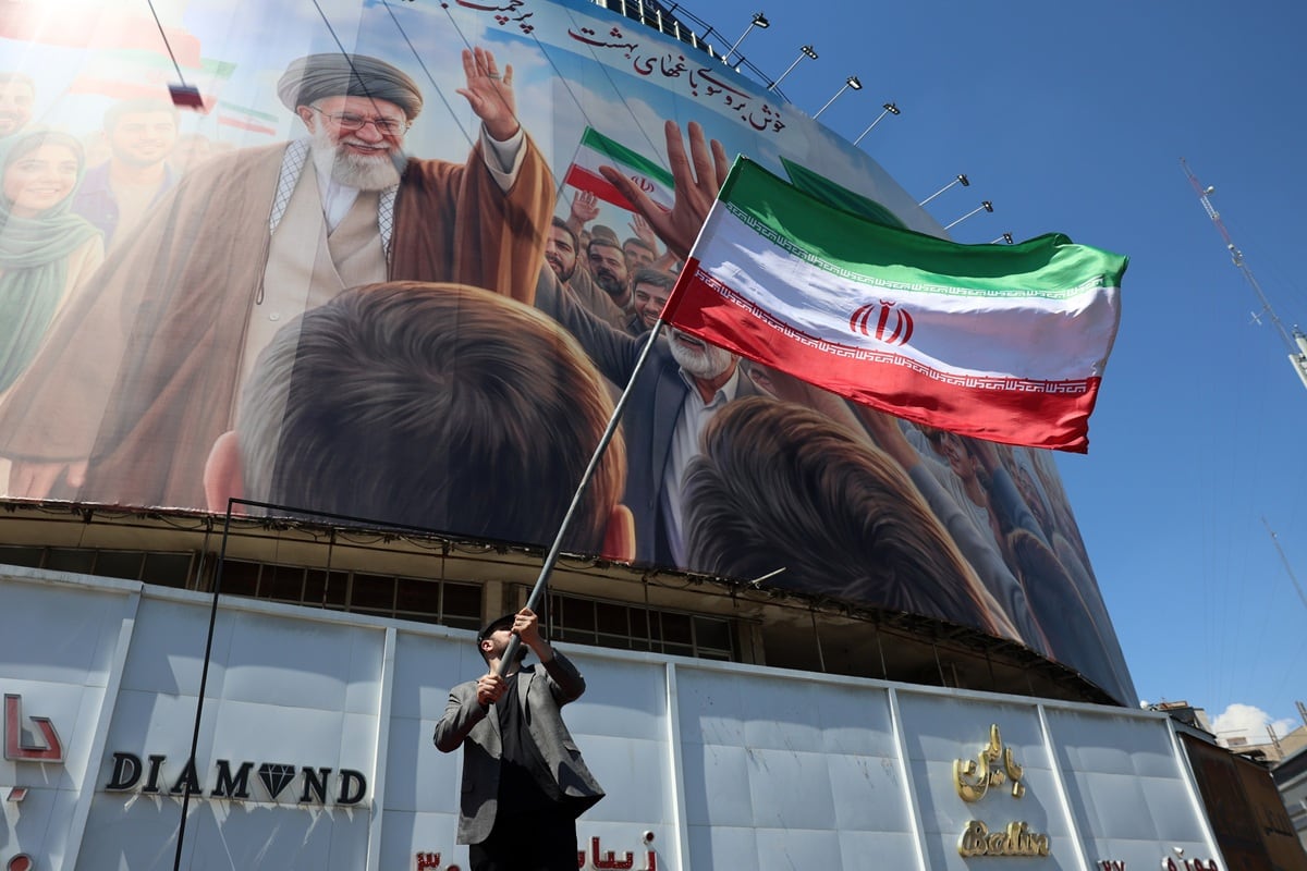 Un hombre iraní ondea la bandera nacional de Irán frente a una gran valla publicitaria que muestra al difunto líder supremo iraní, el ayatolá Ali Jamenei, en la plaza Valiasr de Teherán, Irán, el 10 de abril de 2026. (EFE/EPA/ABEDIN TAHERKENAREH)