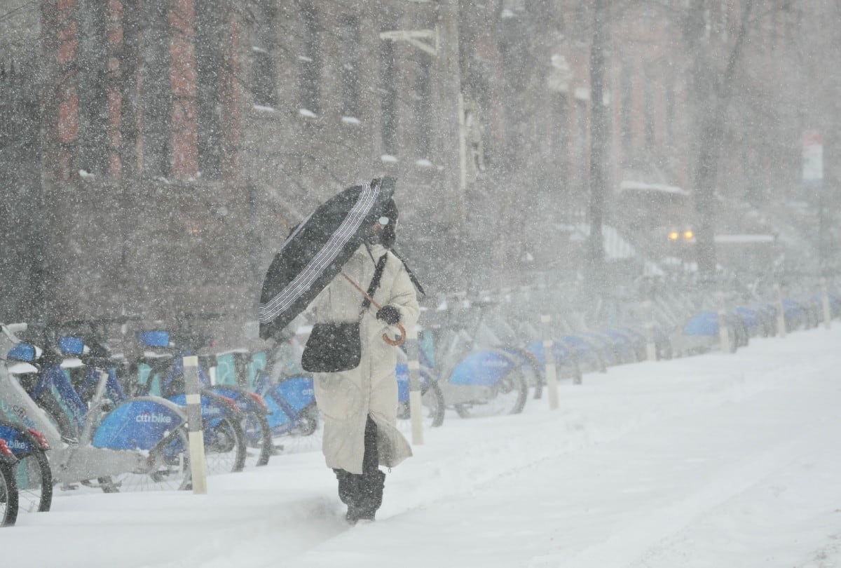 Una mujer camina con paraguas bajo la nieve en Nueva York el 25 de enero de 2026, tras la potente tormenta invernal que azotó gran parte de EE. UU. | Crédito: ANGELA WEISS / AFP