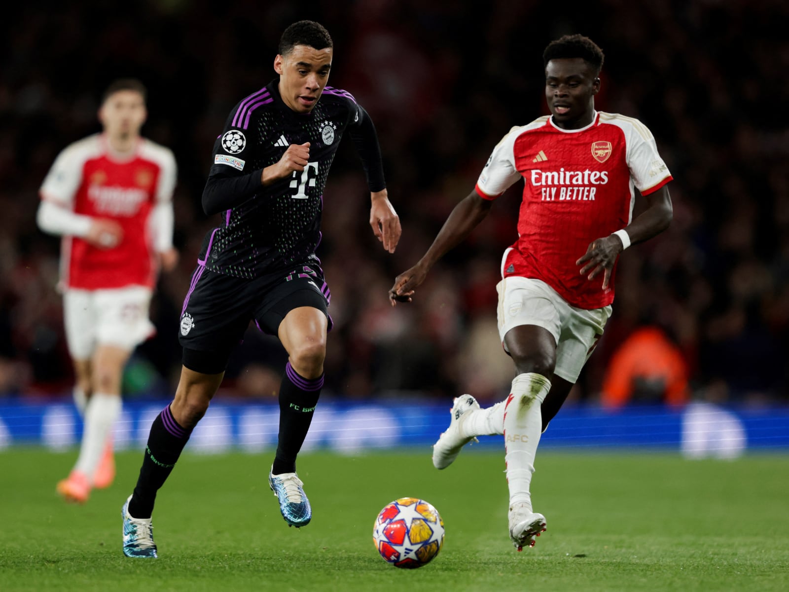 El centrocampista alemán del Bayern de Múnich #42 Jamal Musiala (izq.) lucha por el balón con el centrocampista inglés del Arsenal #07 Bukayo Saka durante el partido de fútbol de ida de cuartos de final de la Liga de Campeones de la UEFA entre el Arsenal y el Bayern de Múnich en el estadio del Arsenal, en el norte de Londres, el 9 de abril de 2024. | Foto: Ian Kington / IKIMAGES / AFP