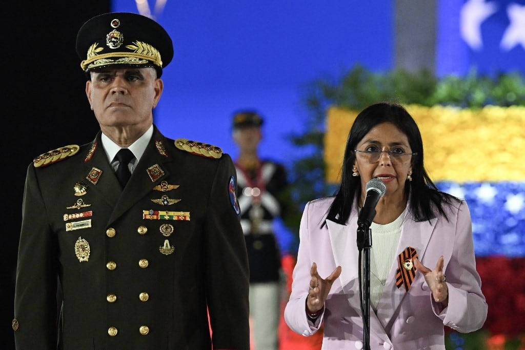 (ARCHIVOS) Delcy Rodríguez (derecha) habla junto al ahora ex ministro de Defensa venezolano, general Vladimir Padrino López, durante un desfile militar en la inauguración de la Plaza de la Victoria, en conmemoración del 80 aniversario de la victoria de la Unión Soviética sobre la Alemania nazi en la Segunda Guerra Mundial, en Caracas, el 13 de mayo de 2025. La presidenta venezolana, Delcy Rodríguez, anunció el 17 de marzo de 2026 la destitución del ministro de Defensa, Vladimir Padrino López, quien dirigió las fuerzas armadas del país durante casi una década bajo el derrocado líder Nicolás Maduro. (Foto de Juan BARRETO / AFP)