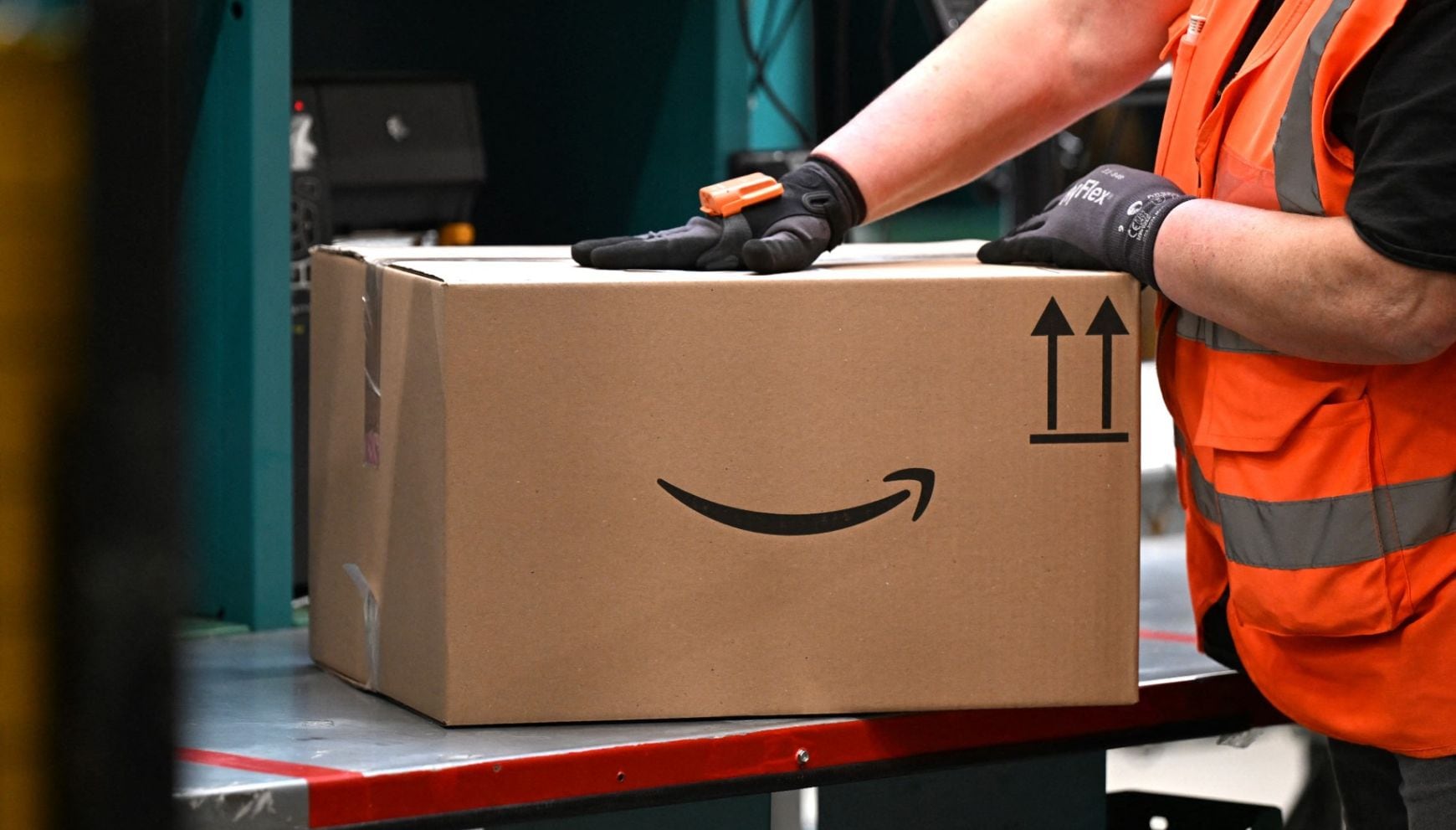 ¿Trabajas en Amazon? La empresa sube el salario mínimo, ofrece nuevos descuentos en comida y más. En la imagen, un trabajador mueve un paquete con el logotipo de Amazon en una estación de embalaje de un centro de redistribución en Werne, en el oeste de Alemania, el 21 de noviembre de 2024 (Foto: Ina Fassbender / AFP)