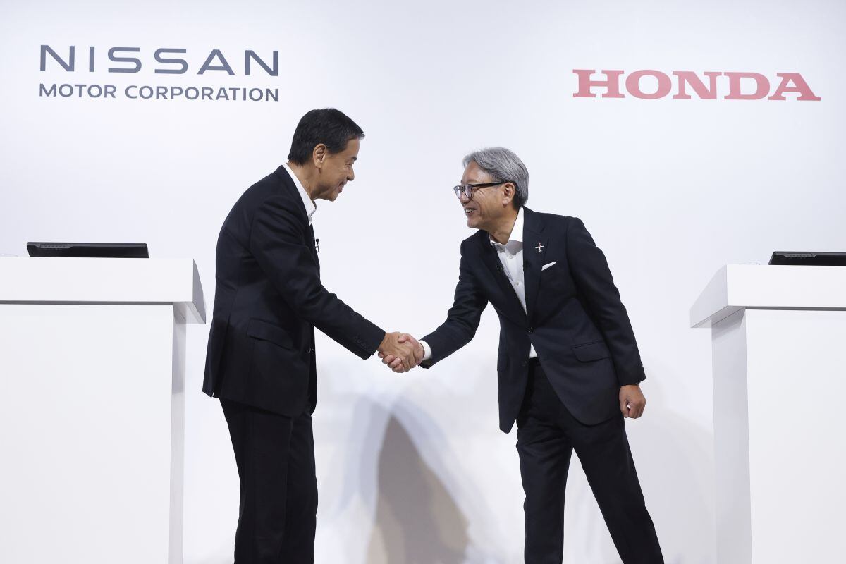 Makoto Uchida, director ejecutivo de Nissan Motor Co., a la izquierda, y Toshihiro Mibe, director ejecutivo de Honda Motor Co., se dan la mano antes de una conferencia de prensa conjunta en Tokio, Japón, el jueves 1 de agosto de 2024. Nissan y Honda acordaron colaborar en software, baterías y otras tecnologías relacionadas con los vehículos eléctricos para ahorrar costos y competir mejor en mercados como China, donde las ventas están cayendo. Fotógrafo: Kiyoshi Ota/Bloomberg