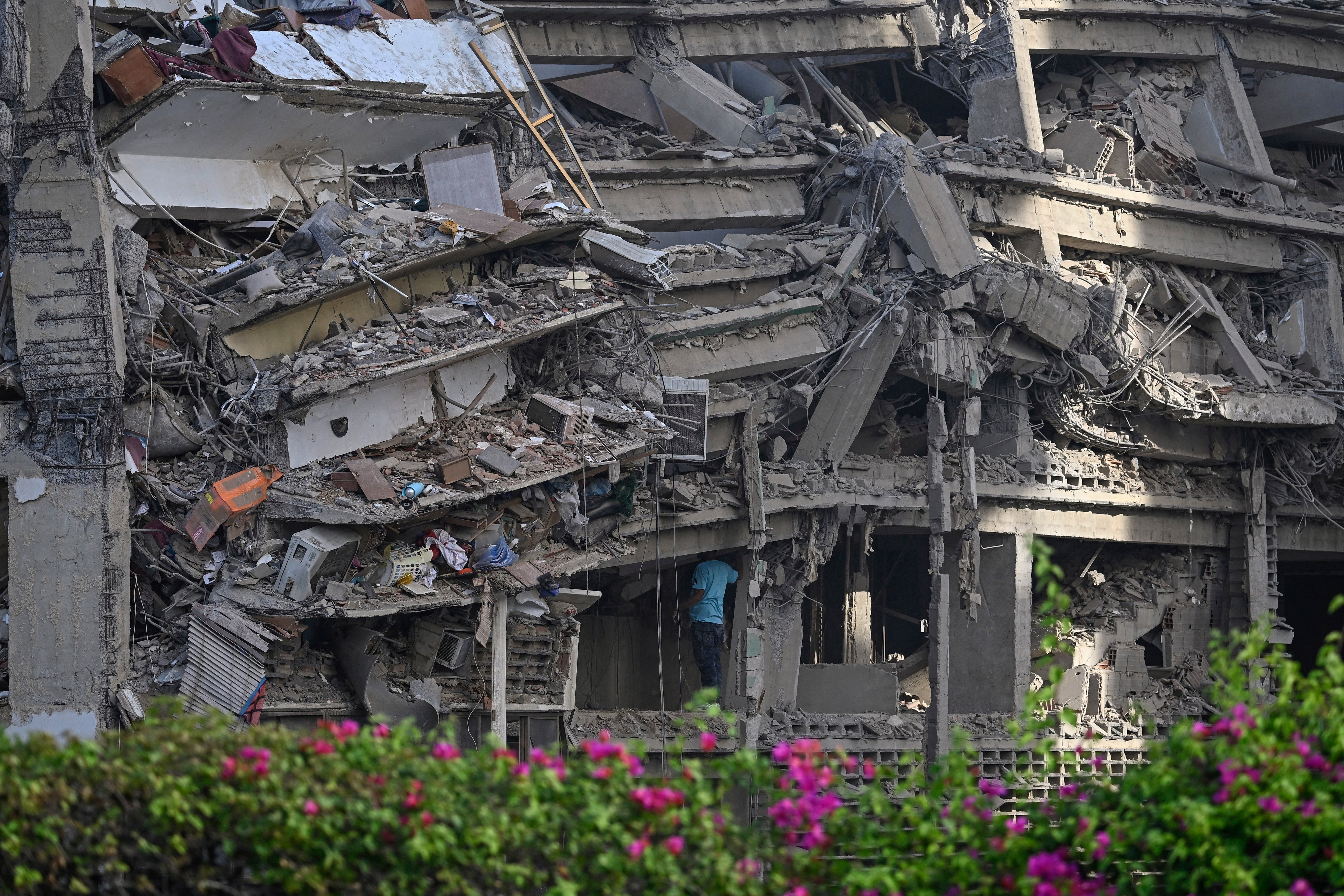 A man inspects a collapsed apartment building following an earthquake in Catia La Mar, La Guaira state, some 30km north-west of Caracas, on June 25, 2026. A twin earthquake that was Venezuela's largest in over a century has killed at least 164 people and destroyed multiple buildings near the capital, where residents searched on June 25 for missing relatives. (Photo by Federico PARRA / AFP)